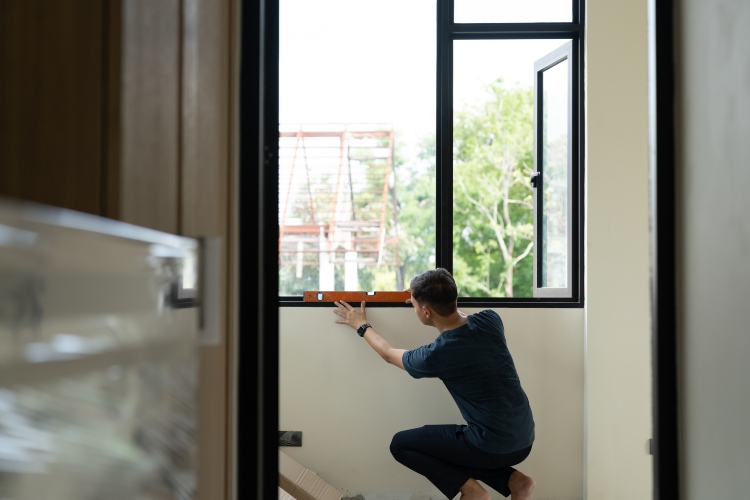 Technician checking window alignment with a level during installation