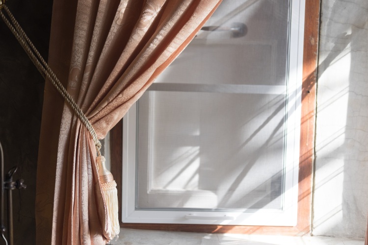 Sunlight shining through a residential window with decorative curtains